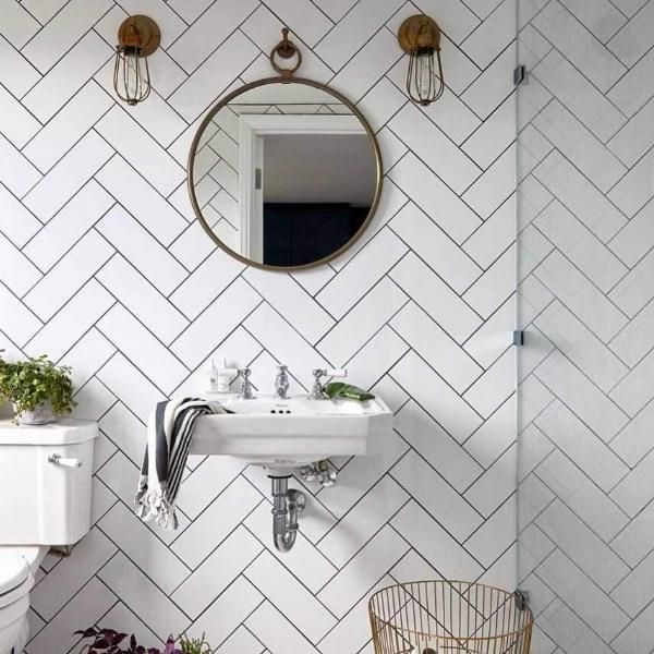 a geometric bathroom with industrial brass cage wall lights. 