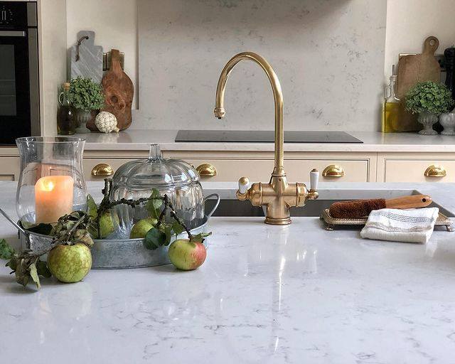 Modern Country kitchen with Brass detailing and marble style worktops with a candle flickering