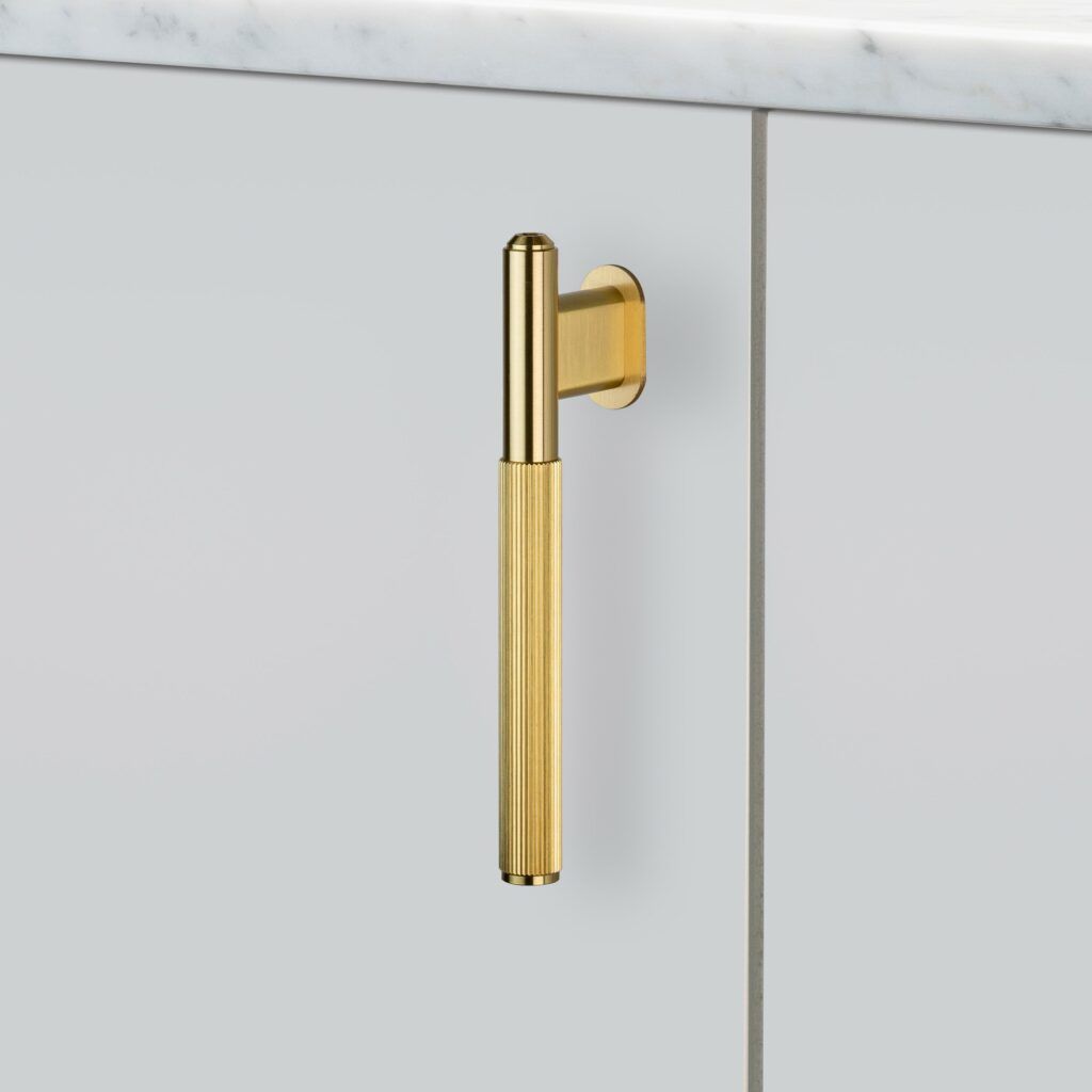 A Brass Buster and Punch L-Bar on a off-white kitchen cupboard